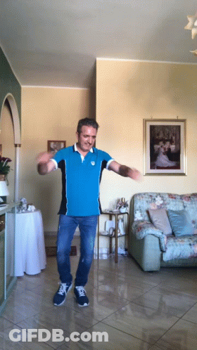 A Man In A Blue Shirt Is Dancing In Front Of A Picture Of A Bride And Groom GIF