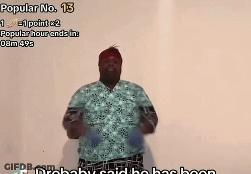 A Man In A Blue Shirt Is Dancing In Front Of A White Wall With The Words Popular No. 13 Above Him GIF