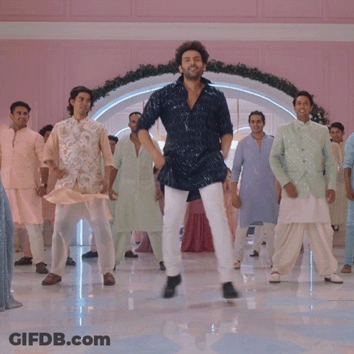 A Man In A Blue Shirt Is Dancing With A Group Of Men In White Pants GIF