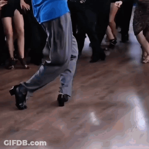 A Man In A Blue Shirt Is Dancing With A Group Of People GIF