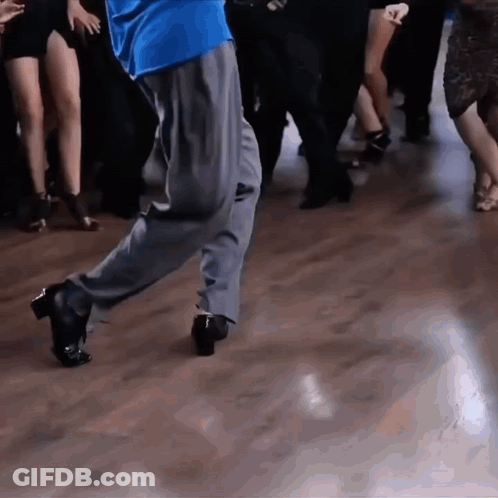 A Man In A Blue Shirt Is Dancing With A Group Of People GIF
