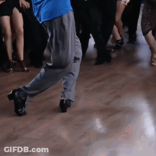 A Man In A Blue Shirt Is Dancing With A Group Of People GIF