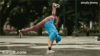A Man In A Blue Shirt Is Doing A Handstand In The Water GIF