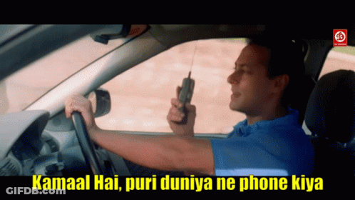 A Man In A Blue Shirt Is Driving A Car While Holding A Cell Phone GIF