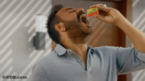 A Man In A Blue Shirt Is Eating A Packet Of Gummy Bears GIF