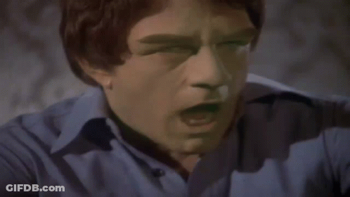 A Man In A Blue Shirt Is Flexing His Arm Muscles GIF