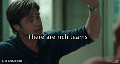 A Man In A Blue Shirt Is Giving A High Five With The Words `` There Are Rich Teams '' Behind Him . GIF