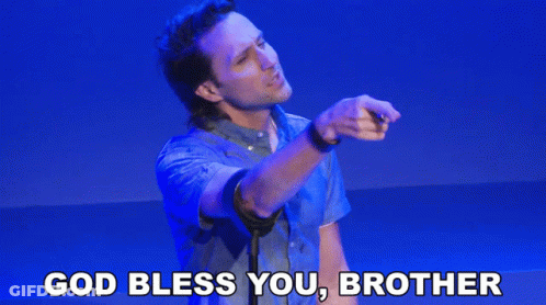 A Man In A Blue Shirt Is Giving A Speech With The Words God Bless You Brother Above Him GIF