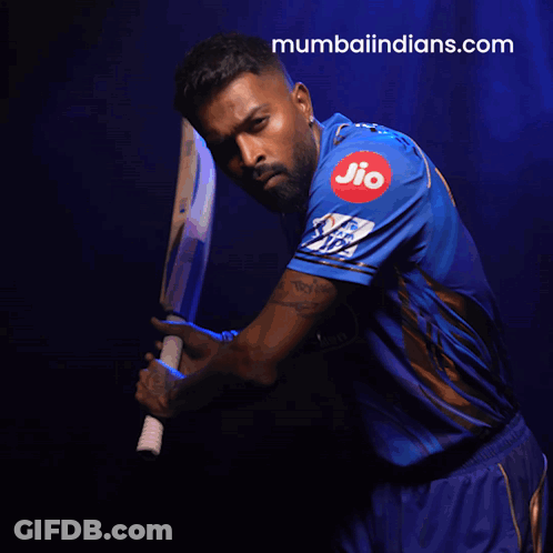 A Man In A Blue Shirt Is Holding A Bat And The Website Mumbaiindians.com Is Visible Behind Him GIF