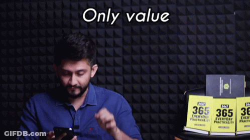 A Man In A Blue Shirt Is Holding A Cell Phone In Front Of A Wall That Says Only Value GIF