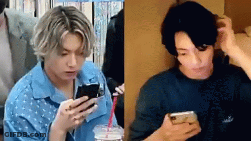 A Man In A Blue Shirt Is Holding A Cell Phone In His Hand . GIF