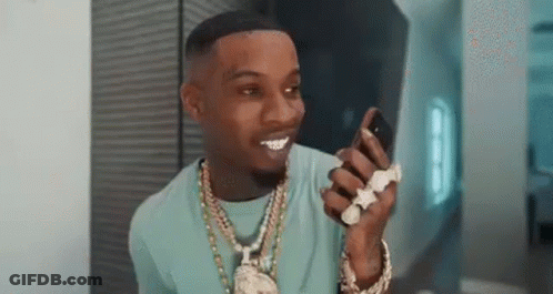 A Man In A Blue Shirt Is Holding A Cell Phone In His Hand . GIF