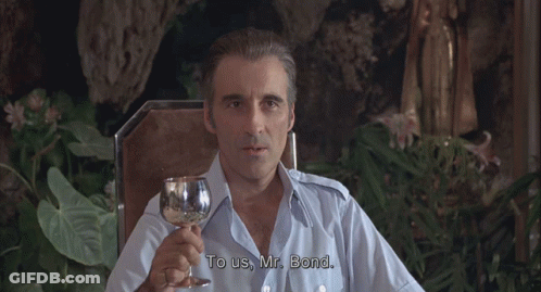 A Man In A Blue Shirt Is Holding A Glass Of Wine GIF