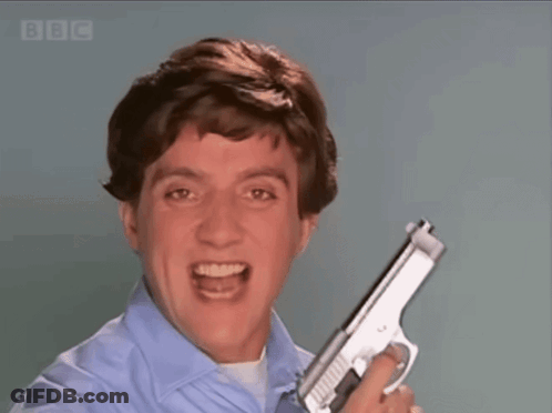 A Man In A Blue Shirt Is Holding A Gun In Front Of A Screen That Says Bbc GIF
