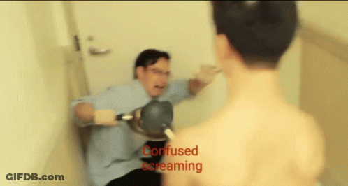 A Man In A Blue Shirt Is Holding A Hair Dryer While Another Man Is Screaming Behind Him GIF