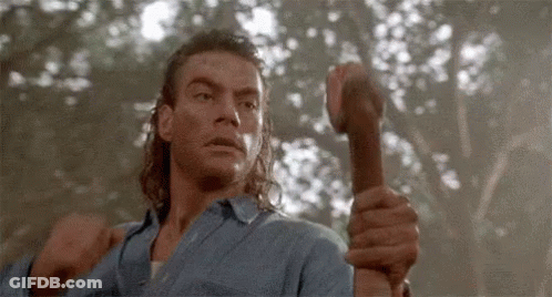 A Man In A Blue Shirt Is Holding A Hammer In His Hand . GIF