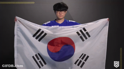A Man In A Blue Shirt Is Holding A Korean Flag In His Hands GIF