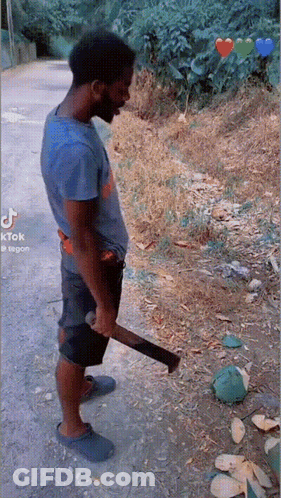 A Man In A Blue Shirt Is Holding A Large Axe In His Hand GIF