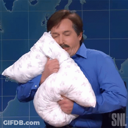 A Man In A Blue Shirt Is Holding A Pillow With The Letters Snl On The Bottom Right GIF