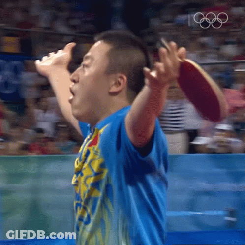 A Man In A Blue Shirt Is Holding A Ping Pong Paddle In His Right Hand GIF