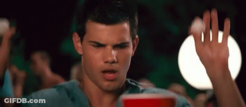 A Man In A Blue Shirt Is Holding A Red Cup In His Hand . GIF
