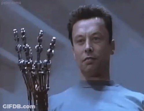 A Man In A Blue Shirt Is Holding A Robotic Arm In His Hand . GIF