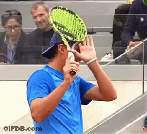 A Man In A Blue Shirt Is Holding A Tennis Racket GIF