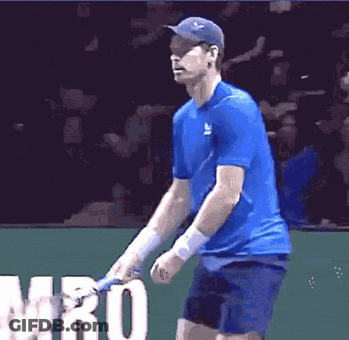 A Man In A Blue Shirt Is Holding A Tennis Racquet In Front Of The Word Mro GIF