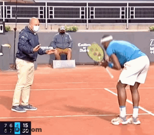 A Man In A Blue Shirt Is Holding A Tennis Racquet On A Tennis Court GIF