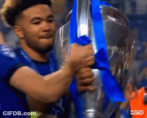 A Man In A Blue Shirt Is Holding A Trophy With A Blue Ribbon And The Word Heiitse On The Bottom GIF