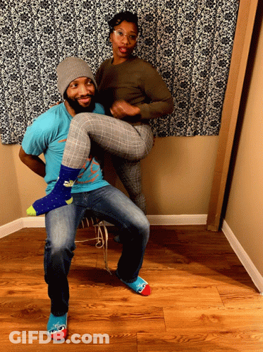 A Man In A Blue Shirt Is Holding A Woman 'S Legs GIF