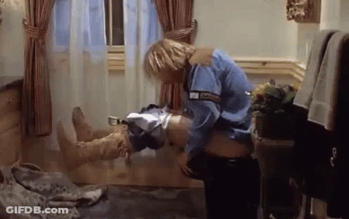 A Man In A Blue Shirt Is Holding A Woman 'S Stomach In A Room . GIF