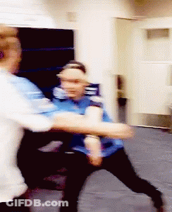 A Man In A Blue Shirt Is Holding Another Man 'S Arm GIF