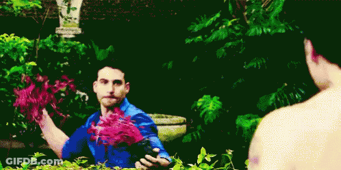 A Man In A Blue Shirt Is Holding Flowers In His Hands GIF
