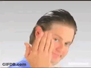 A Man In A Blue Shirt Is Holding His Hand To His Face And Smiling . GIF