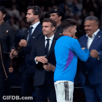 A Man In A Blue Shirt Is Hugging A Man In A Suit . GIF
