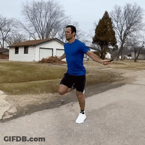 A Man In A Blue Shirt Is Jumping A Jump Rope On A Road GIF