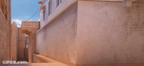 A Man In A Blue Shirt Is Jumping In The Air In Front Of A Building With A Sign That Says ' Ambulance ' GIF