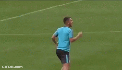 A Man In A Blue Shirt Is Kicking A Soccer Ball On A Soccer Field . GIF