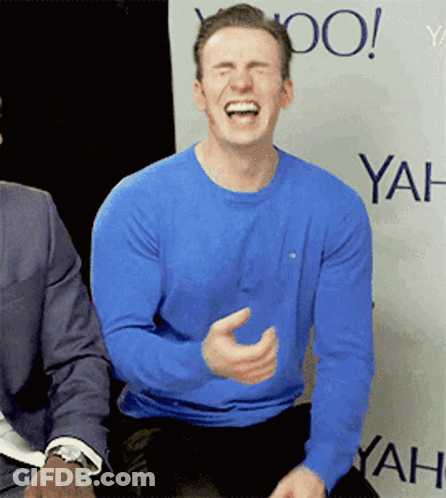 A Man In A Blue Shirt Is Laughing In Front Of A Wall That Says Yahoo GIF