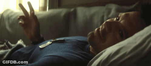 A Man In A Blue Shirt Is Laying In Bed With His Eyes Closed GIF