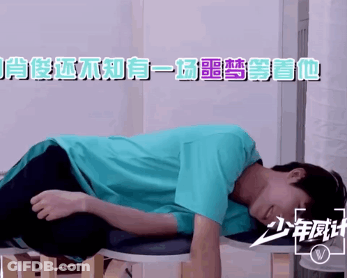 A Man In A Blue Shirt Is Laying On A Stool With Chinese Writing On It GIF