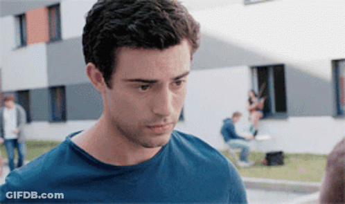A Man In A Blue Shirt Is Looking At Something GIF