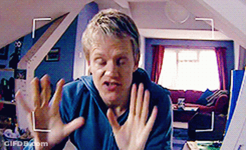 A Man In A Blue Shirt Is Making A Funny Face In Front Of A Camera GIF