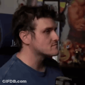A Man In A Blue Shirt Is Making A Funny Face While Holding His Finger To His Lips . GIF