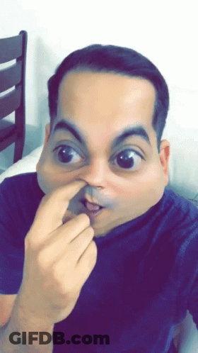 A Man In A Blue Shirt Is Making A Funny Face With His Finger In His Nose GIF