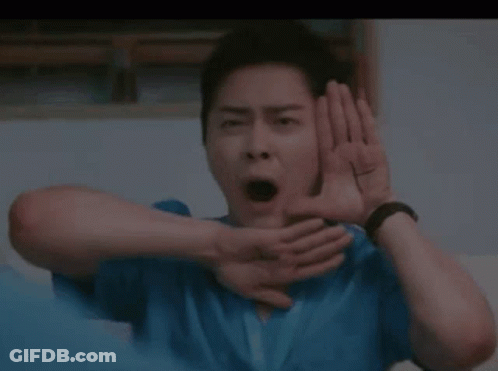 A Man In A Blue Shirt Is Making A Funny Face With His Hands Behind His Ears . GIF