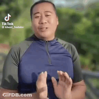 A Man In A Blue Shirt Is Making A Funny Face With His Hands In Front Of His Face . GIF