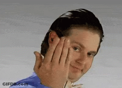 A Man In A Blue Shirt Is Making A Funny Face With His Hands . GIF