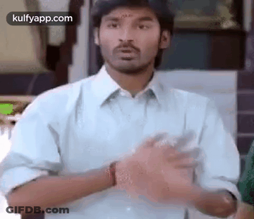 A Man In A Blue Shirt Is Making A Funny Face With His Hands . GIF